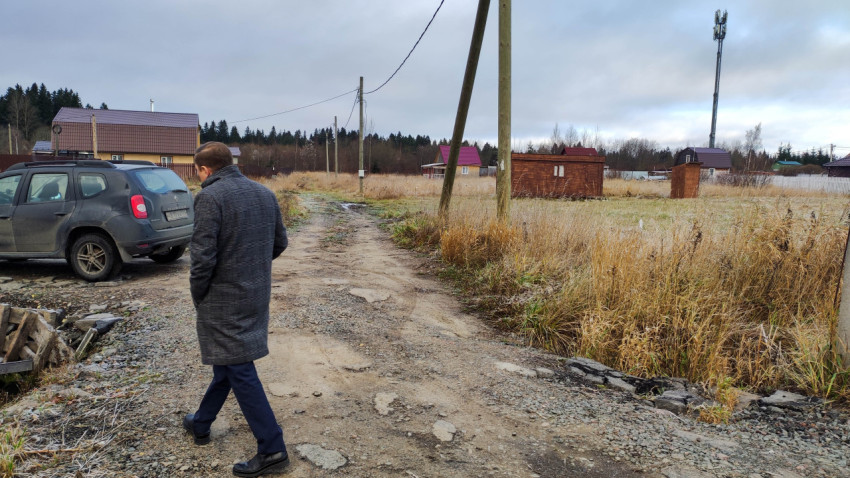 Мужчина в пальто на грунтовой дороге в сельской местности с электростолбами