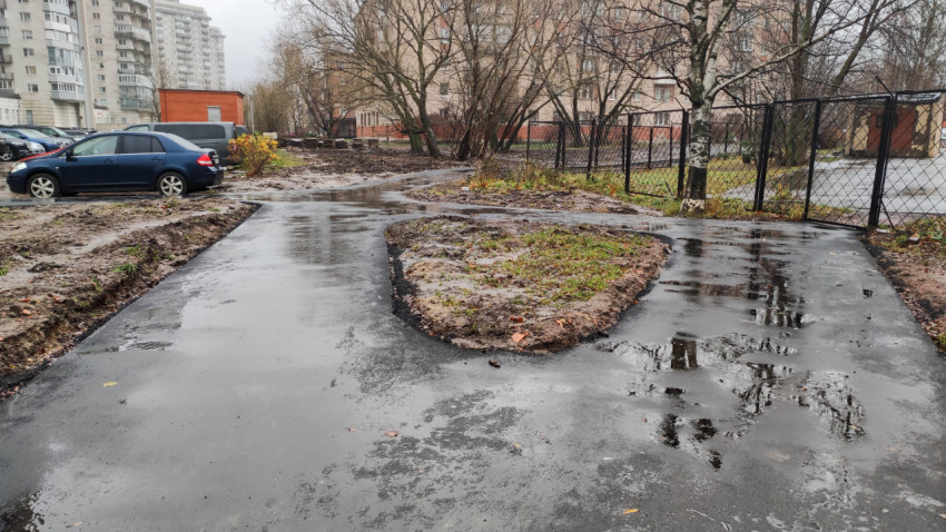 Новый асфальтированный тротуар во дворе с лужами после дождя