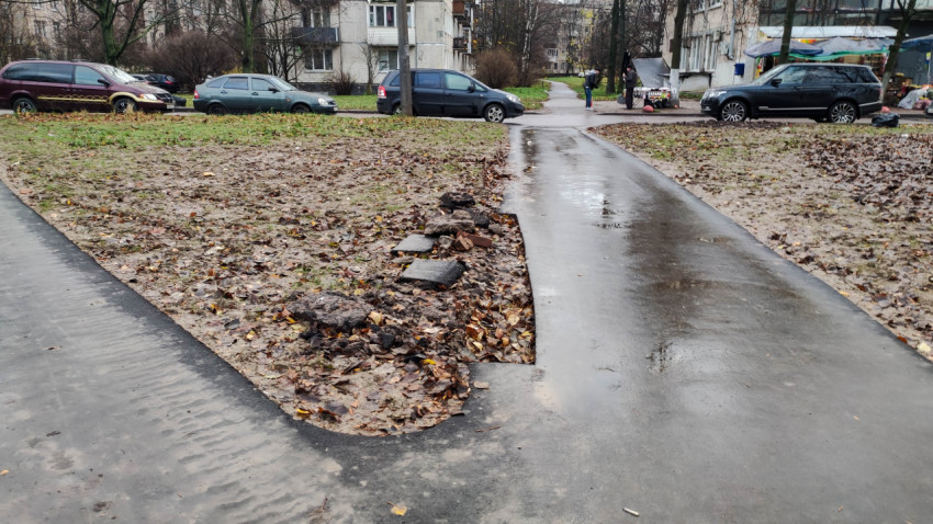Повреждённый асфальтированный тротуар во дворе жилого дома