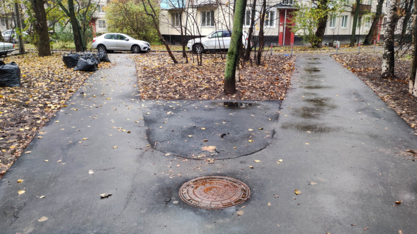 Люк на асфальтированной дорожке во дворе многоквартирного дома