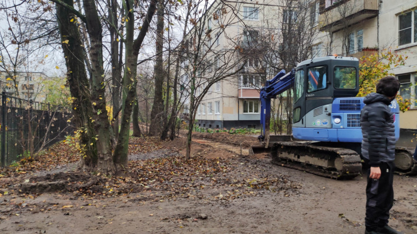 Земляные работы во дворе жилого дома с использованием экскаватора