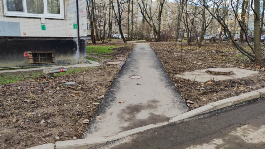 Пешеходная дорожка возле жилого дома с канализационными люками