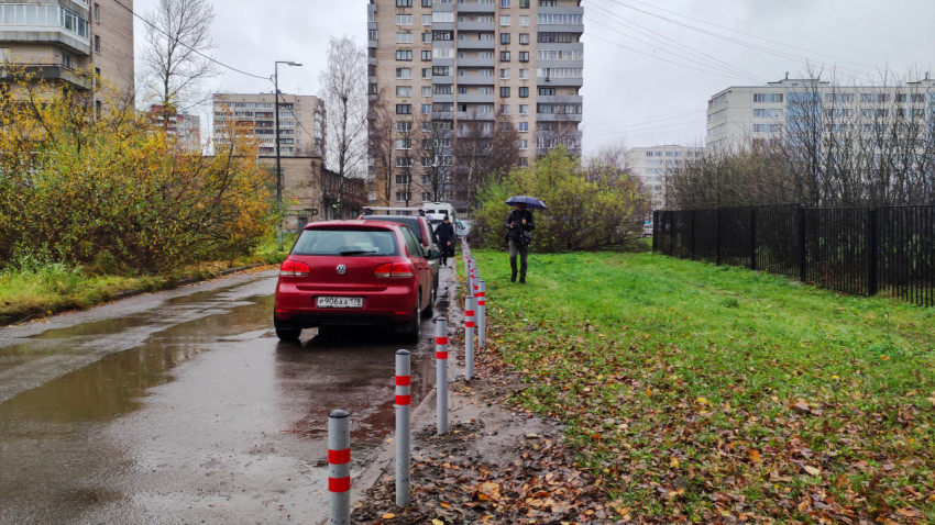 Ряд антипарковочных столбиков на мокрой дороге в жилом районе после дождя