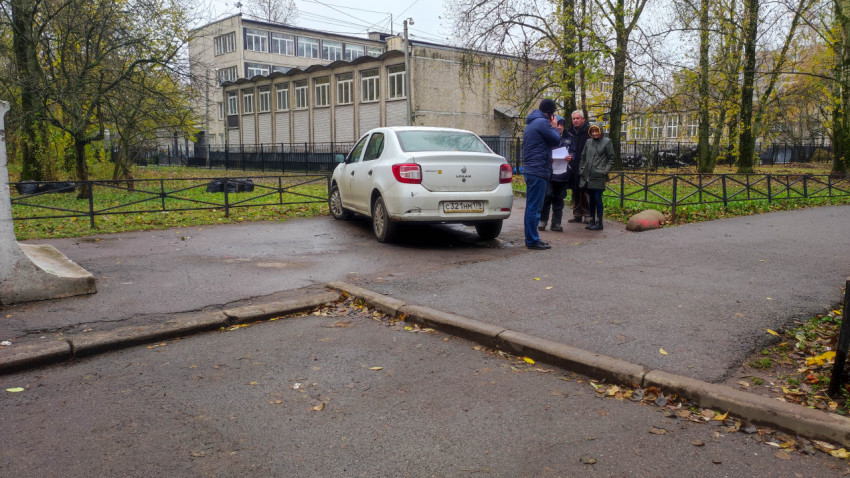 Группа людей на пешеходной дорожке возле припаркованного автомобиля