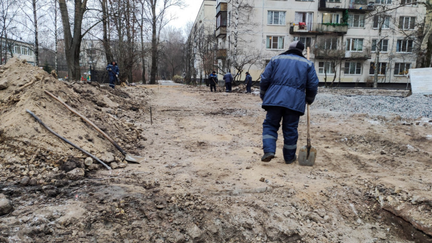 Рабочие проводят подготовку грунта перед укладкой дорожного покрытия во дворе жилого дома