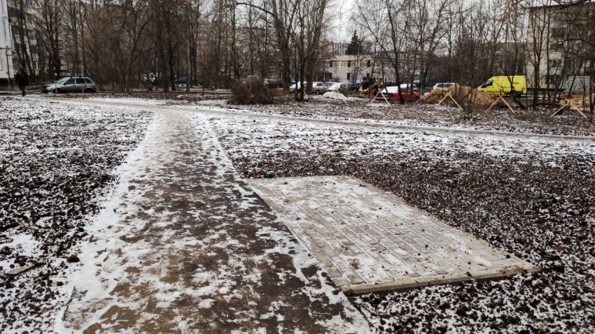 Фрагмент пешеходной дорожки с выложенной плиткой площадкой во дворе жилого дома
