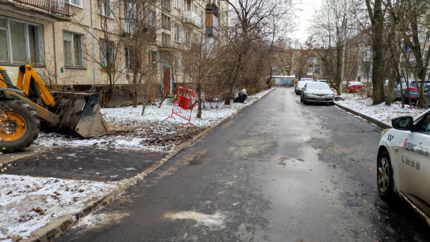 Зимний жилой двор с дорожными работами, экскаватором и припаркованными автомобилями