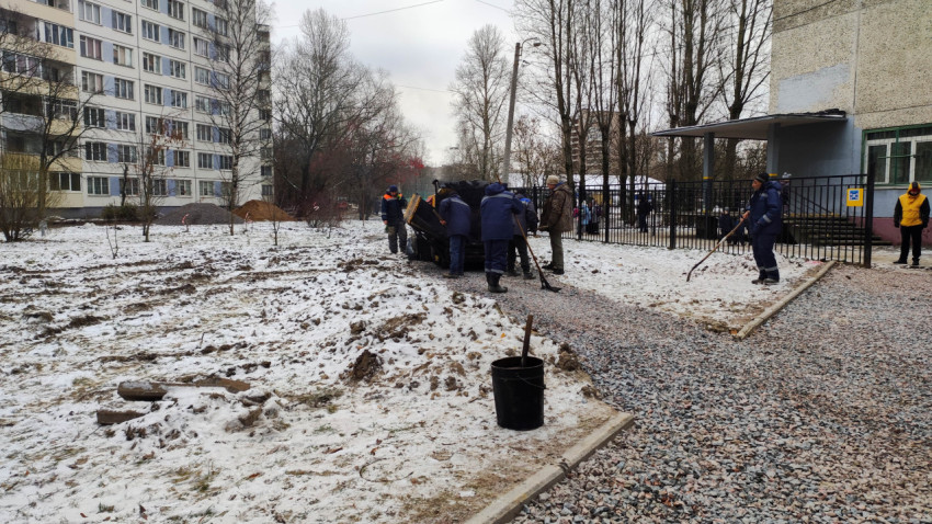 Рабочие укладывают асфальт на пешеходной дорожке зимой