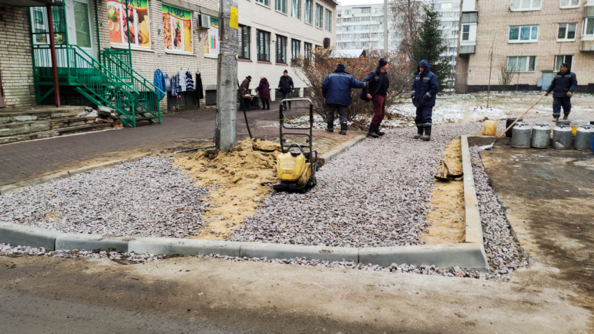 Рабочие укладывают основание тротуара у магазина