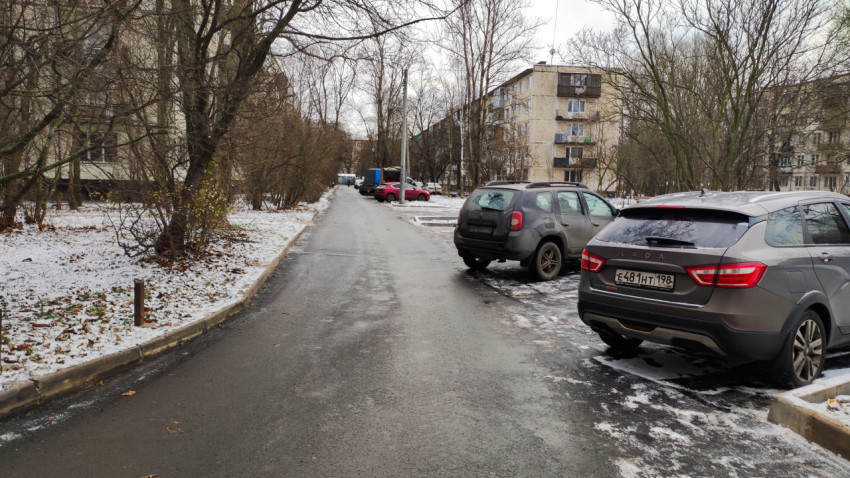 Зимний жилой двор с припаркованными автомобилями и асфальтированной дорогой