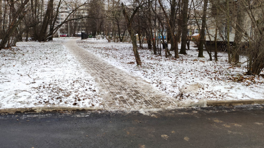 Зимняя дворовая территория с пешеходной дорожкой из брусчатки и асфальтированной дорогой