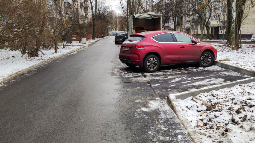 Зимняя дворовая парковка с припаркованным автомобилем и асфальтированной дорогой