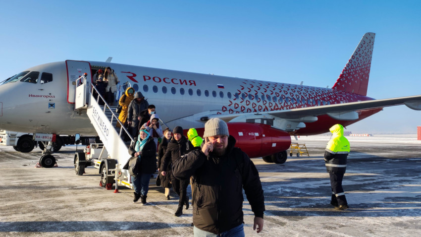 Пассажиры выходят из самолета в зимнем аэропорту