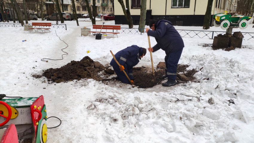 Два рабочих копают яму для установки игрового оборудования на детской площадке