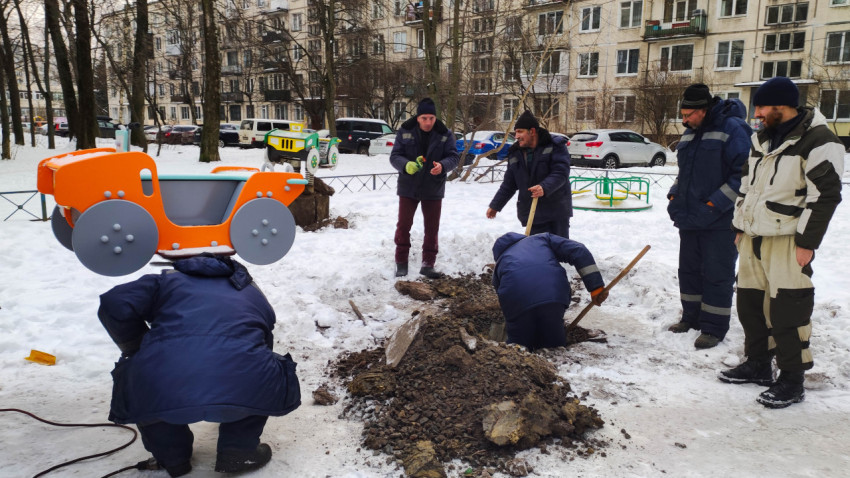 Рабочие устанавливают игровую качалку на пружине на детской площадке зимой