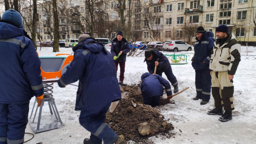 Рабочие устанавливают качалку на пружине на детской площадке зимой