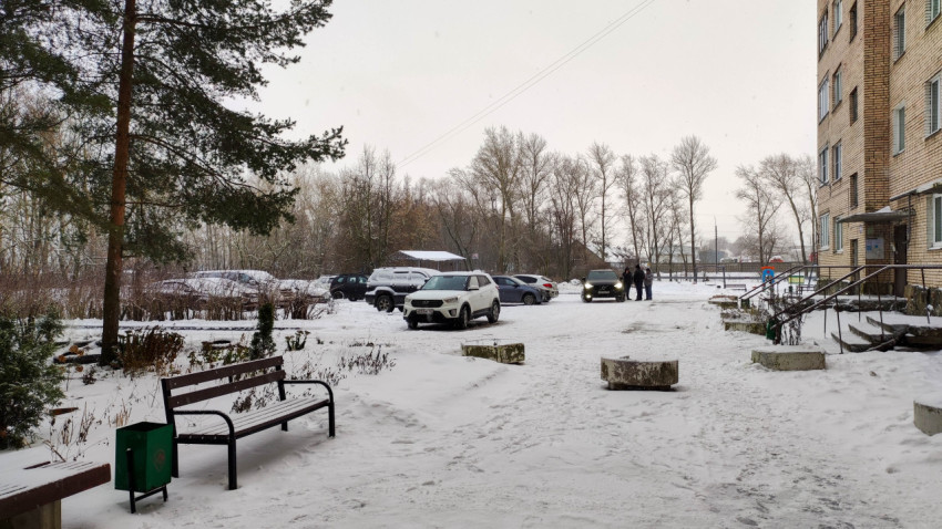 Заснеженный двор многоквартирного дома с парковкой и городской инфраструктурой