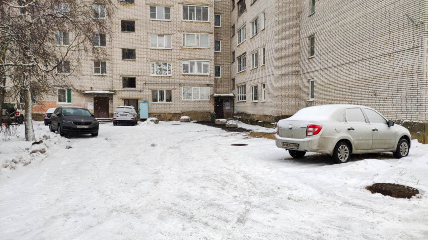 Заснеженный двор многоквартирного дома с припаркованными машинами