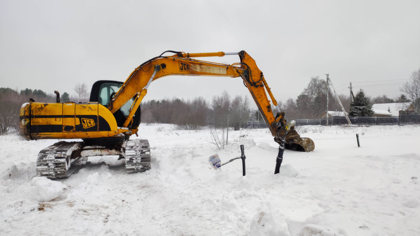 Гусеничный экскаватор JCB на заснеженном участке во время строительных работ