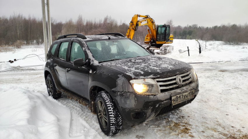 Автомобиль Renault Duster на зимней стройке с экскаватором
