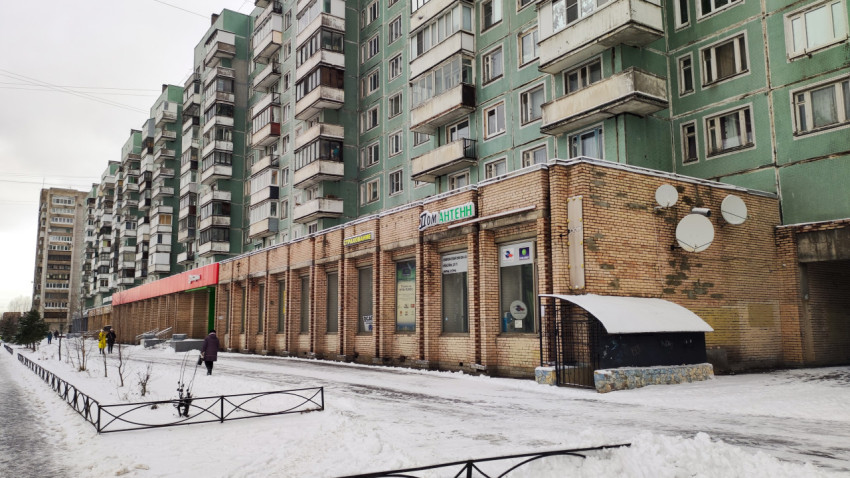 Типовая панельная многоэтажка с магазинами на первом этаже зимой