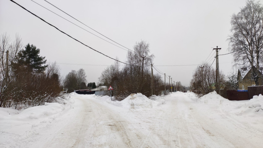 Развилка деревенских улиц зимой с дорожным знаком и ЛЭП
