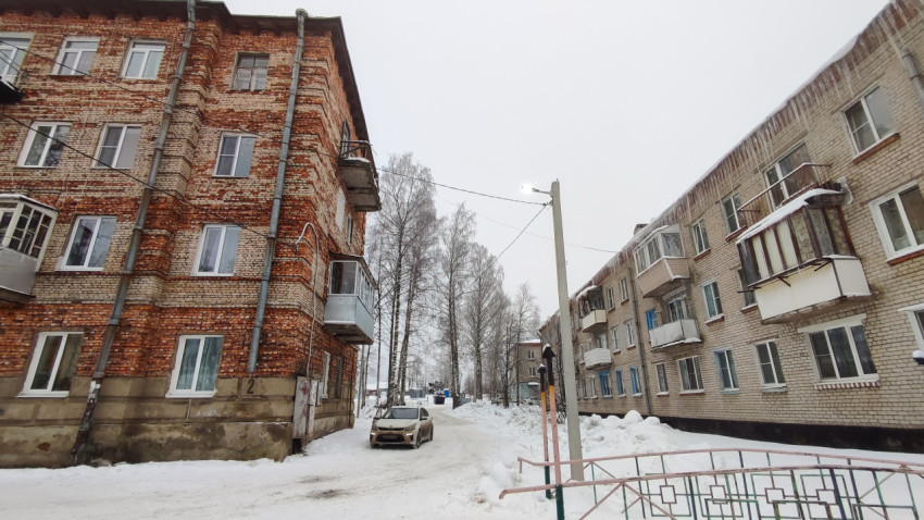 Двор между многоквартирными домами зимой с автомобилем и фонарём