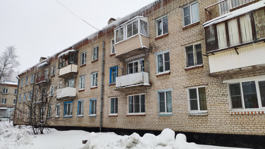 Фрагмент старого жилого дома с балконами и сосульками в зимнее время