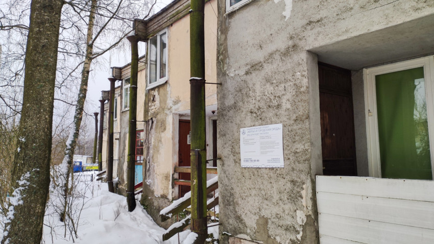 Фасад аварийного дома с табличкой нацпроекта «Жильё и городская среда»
