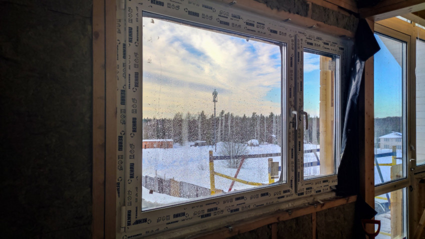 Окно REHAU в строящемся доме с видом на зимний участок и лес