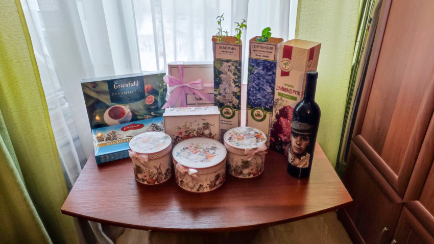 Подарочные наборы с чаем, сладостями и саженцами на столе