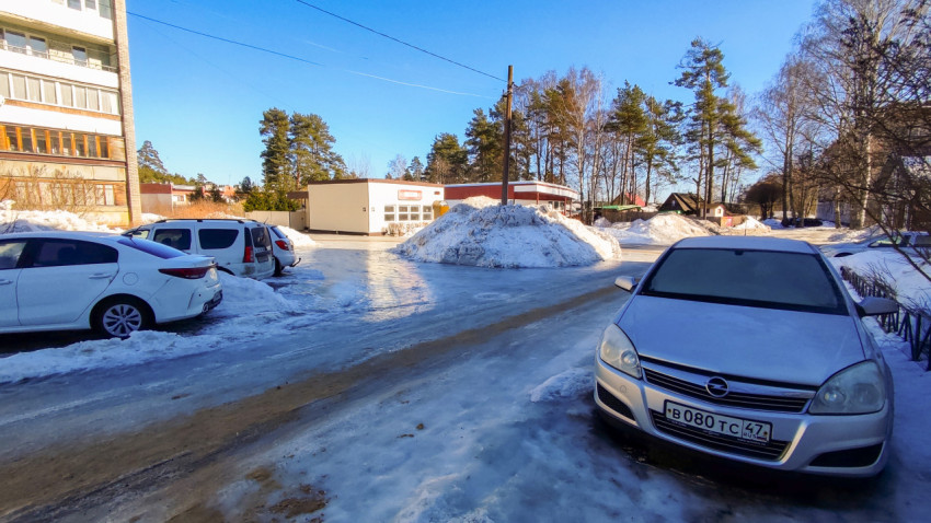 Автомобили припаркованы вдоль дороги у магазина зимой