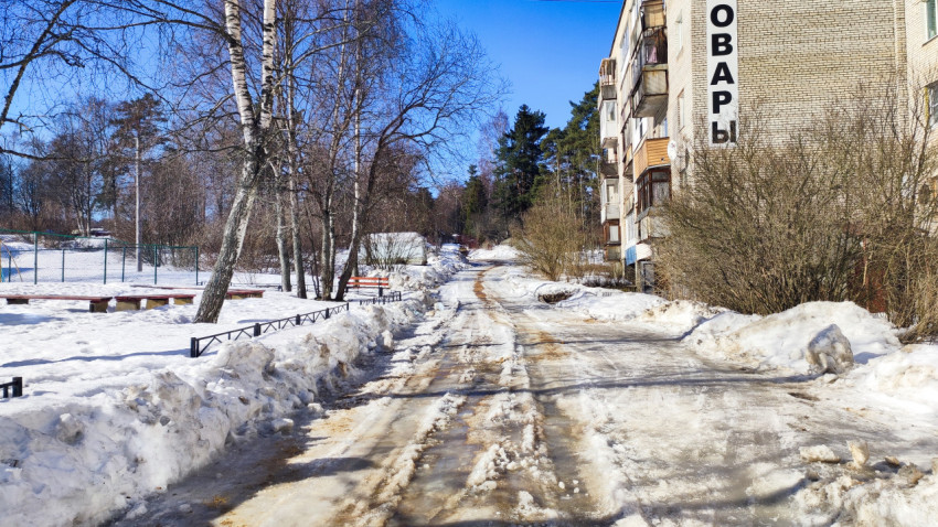 Дворовая дорога в снегу с жилыми домами и ограждениями