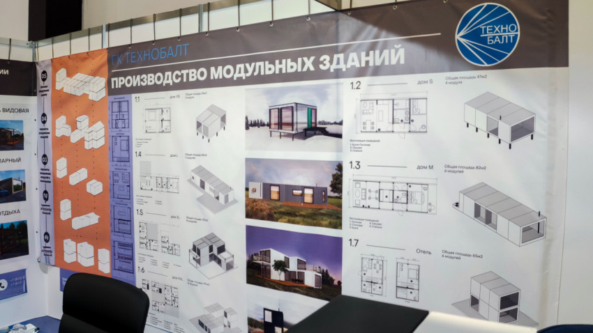 Панель с чертежами и визуализациями модульных домов на выставке