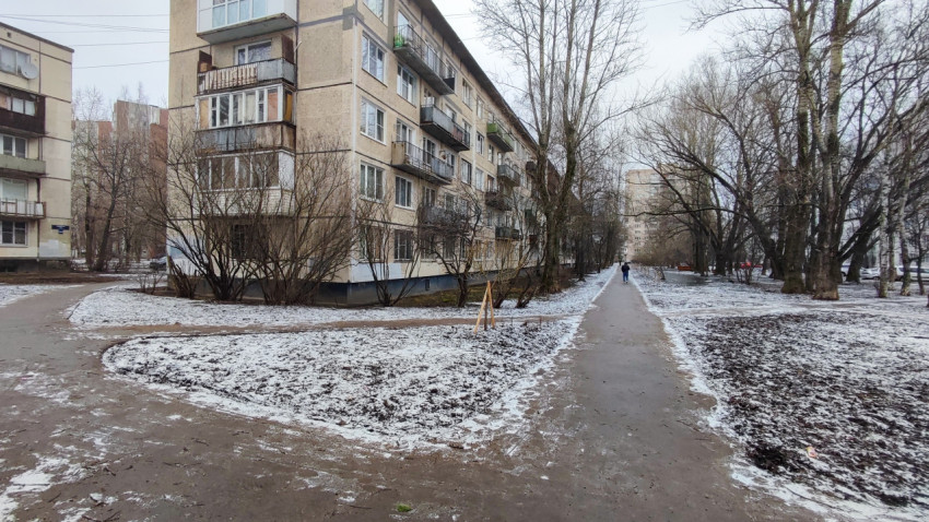 Длинная пешеходная дорожка вдоль жилого дома зимой