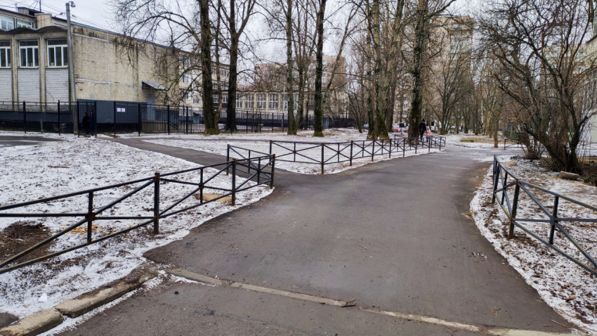 Асфальтированная дорожка вдоль ограждения школы зимой