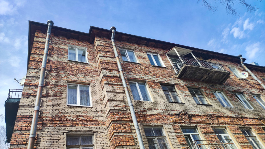 Фрагмент фасада кирпичного жилого дома с балконом