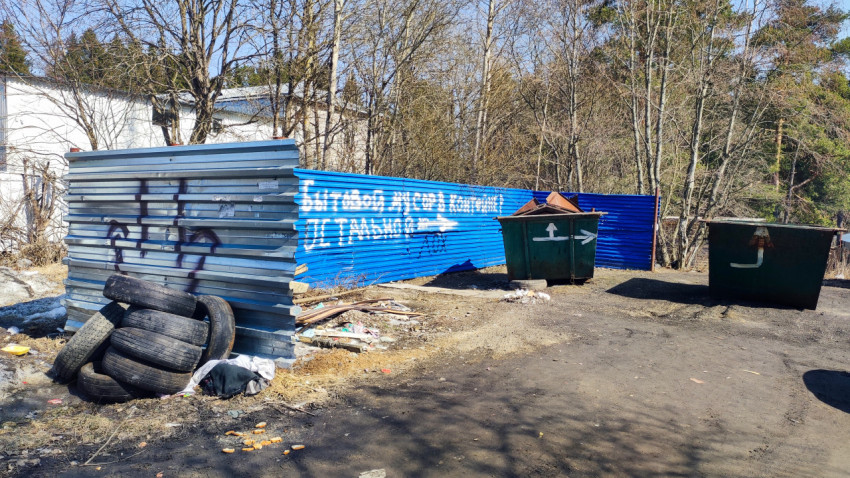 Контейнерная площадка и металлический забор с надписью о мусоре