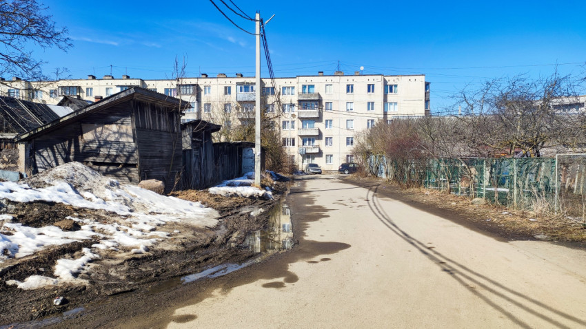 Асфальтированная дорога с лужами и остатками снега в жилом квартале