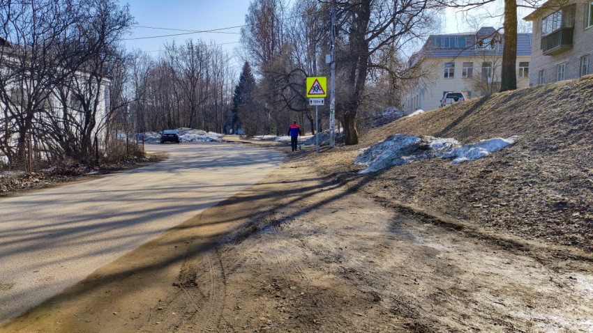 Пешеход у знака перехода на весенней дороге