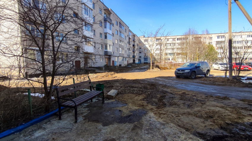 Двор с грязной территорией и припаркованными автомобилями весной