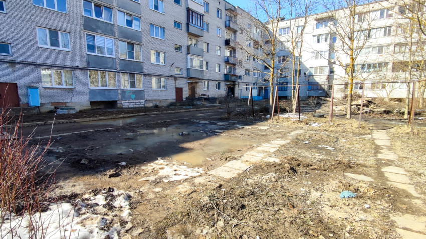 Двор с лужами и грязью между многоквартирными домами весной