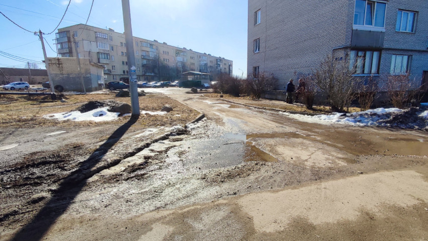 Весенний двор с тающим снегом и грязной дорогой возле домов