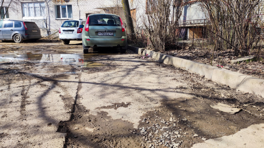 Автомобиль припаркован во дворе на фоне подъезда жилого дома