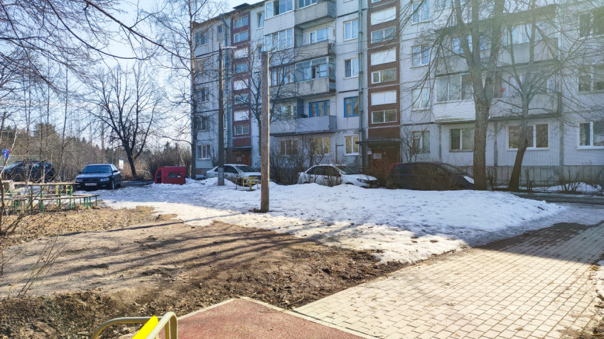 Многоквартирный дом и припаркованные машины на фоне тающего снега