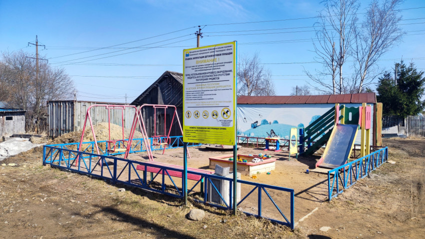 Детская площадка в деревне с предупреждающим щитом