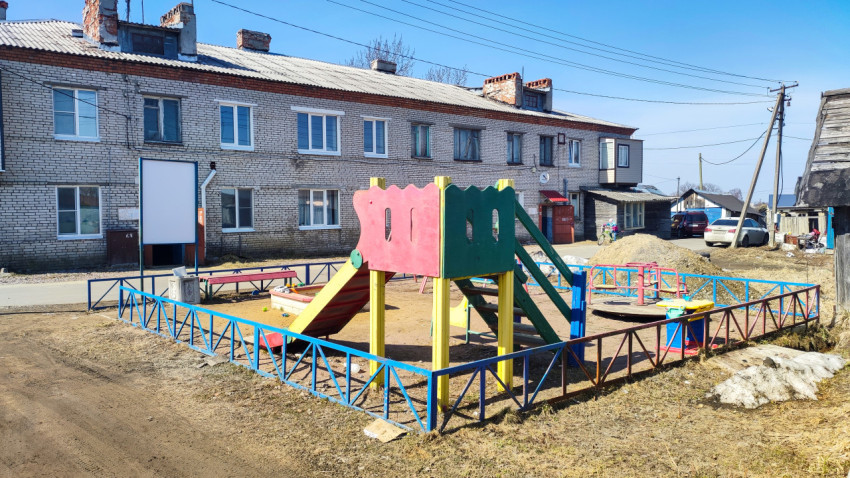 Игровая площадка на фоне кирпичного дома в сельской местности