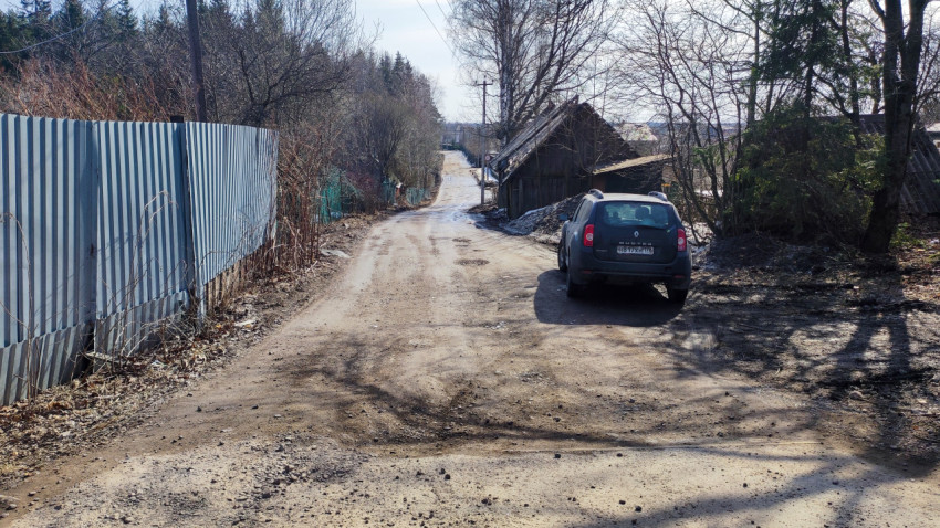 Грунтовая дорога в деревне с припаркованной машиной