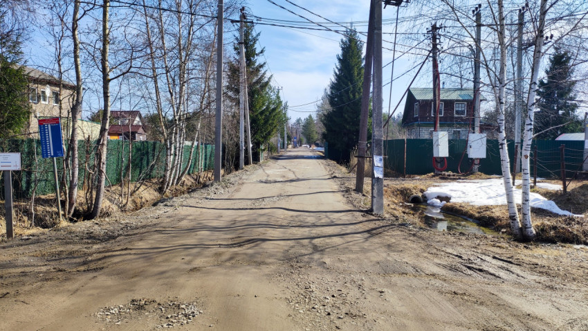 Просёлочная дорога вдоль заборов и ручья в дачном посёлке