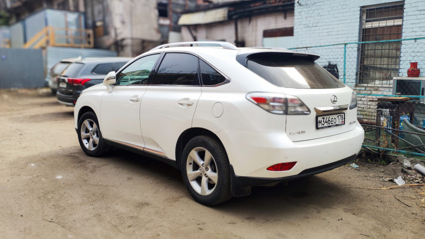 Белый кроссовер Lexus RX 450h на парковке у здания